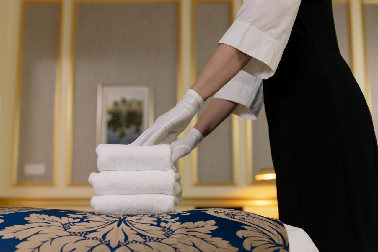mobile-02 A hotel housekeeper neatly stacks fresh towels in a luxurious room setting.